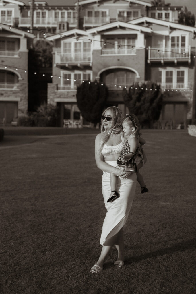 Mother and daughter dressed in vintage fashion walk outdoors in black and white image.
