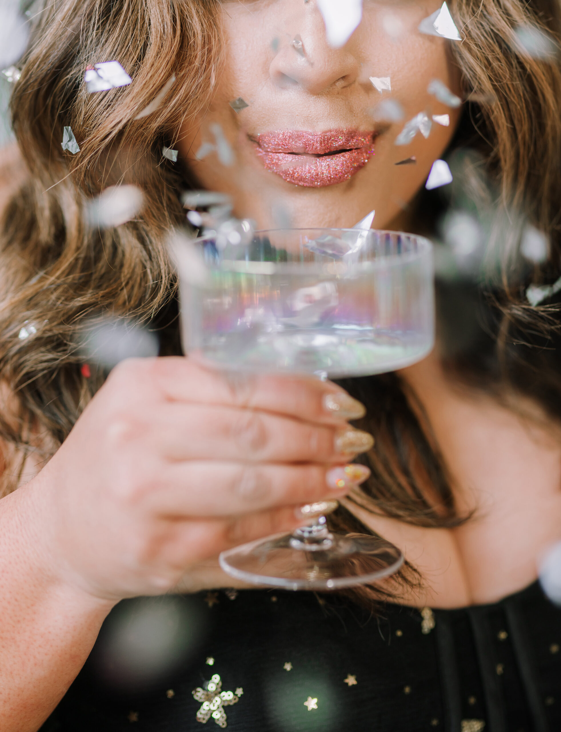 Close-up branding photo of a woman with glittery lips, holding a champagne glass amid falling confetti — a playful and bold image that highlights the kind of creative visuals you can expect when you ask the right questions to your brand photographer before booking. Captured in Greenville, SC by Dani Lacey Photographs.

