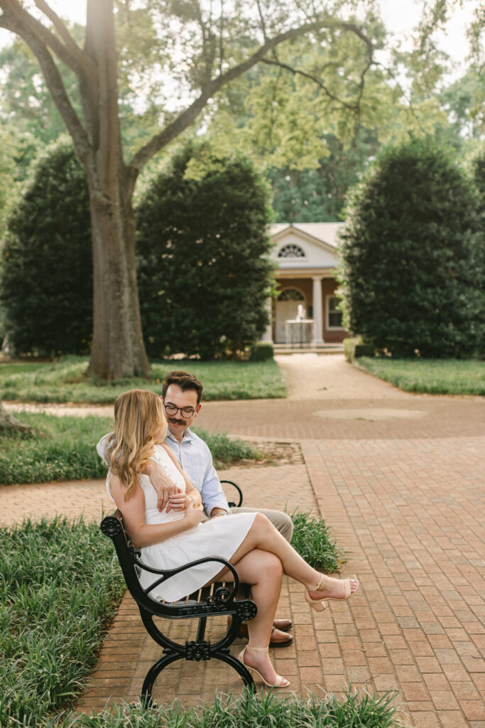 Couple sitting closely on a black iron bench in a quiet park at Furman University, one of the easy photo spots in Greenville SC – Dani Lacey Photographs