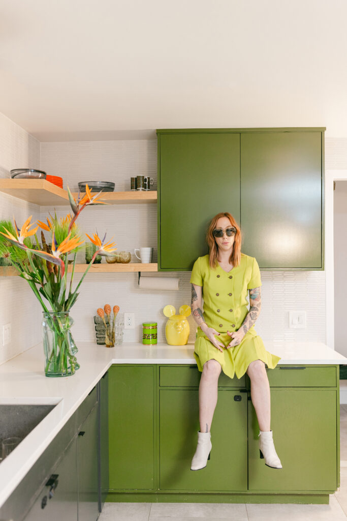 Bold editorial branding portrait of a woman in a lime green dress seated on a modern green kitchen counter, captured in Greenville SC by Dani Lacey.