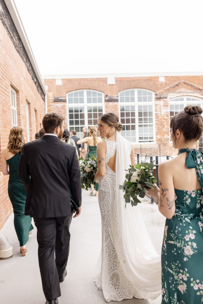 Bride and groom walking with their bridal party through a historic brick venue in Greenville, SC — a candid, editorial-style moment Dani Lacey Photographs.