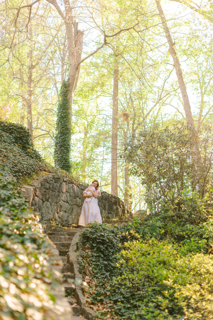 A mother and baby stand on a stone path lined with ivy at Falls Park in Greenville SC.