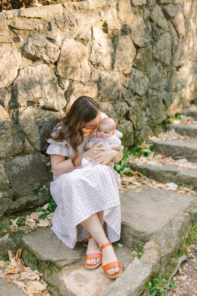 A mom cuddles her baby while sitting on stone steps at Falls Park in Greenville SC.