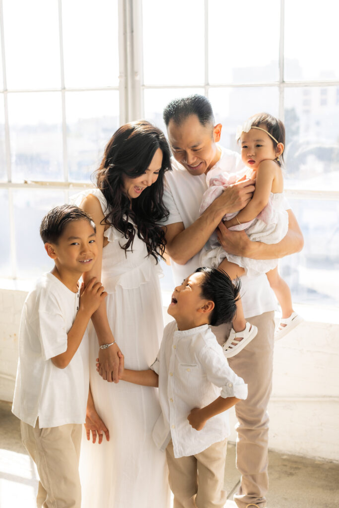 Family of five laughing and connection in a bright, window-lit studio