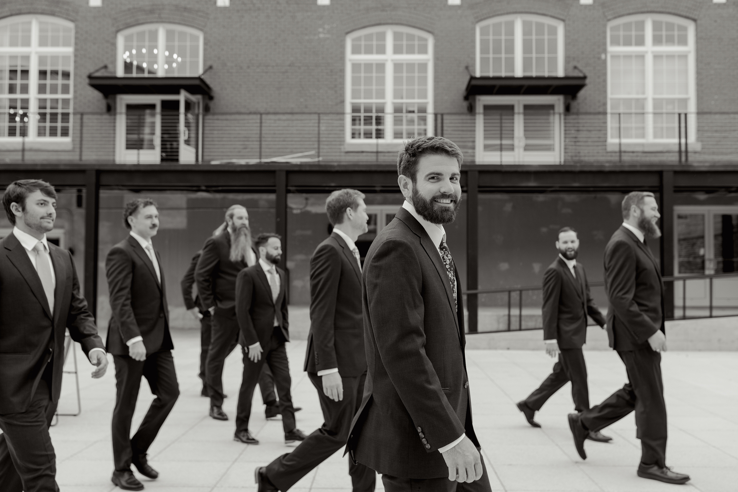 Candid editorial-style moment of groom and groomsmen walking through a downtown Greenville SC wedding venue – captured with the help of a second shooter by Dani Lacey Photographs.