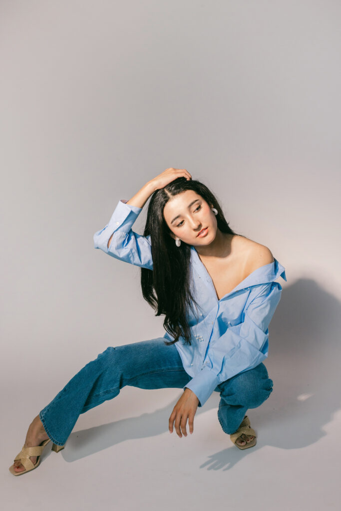 Studio branding portrait of a woman in a light blue shirt and denim, striking a casual editorial pose — a perfect example of intentional styling that comes from asking the right questions to your brand photographer before booking. Captured by Dani Lacey in Greenville, SC.