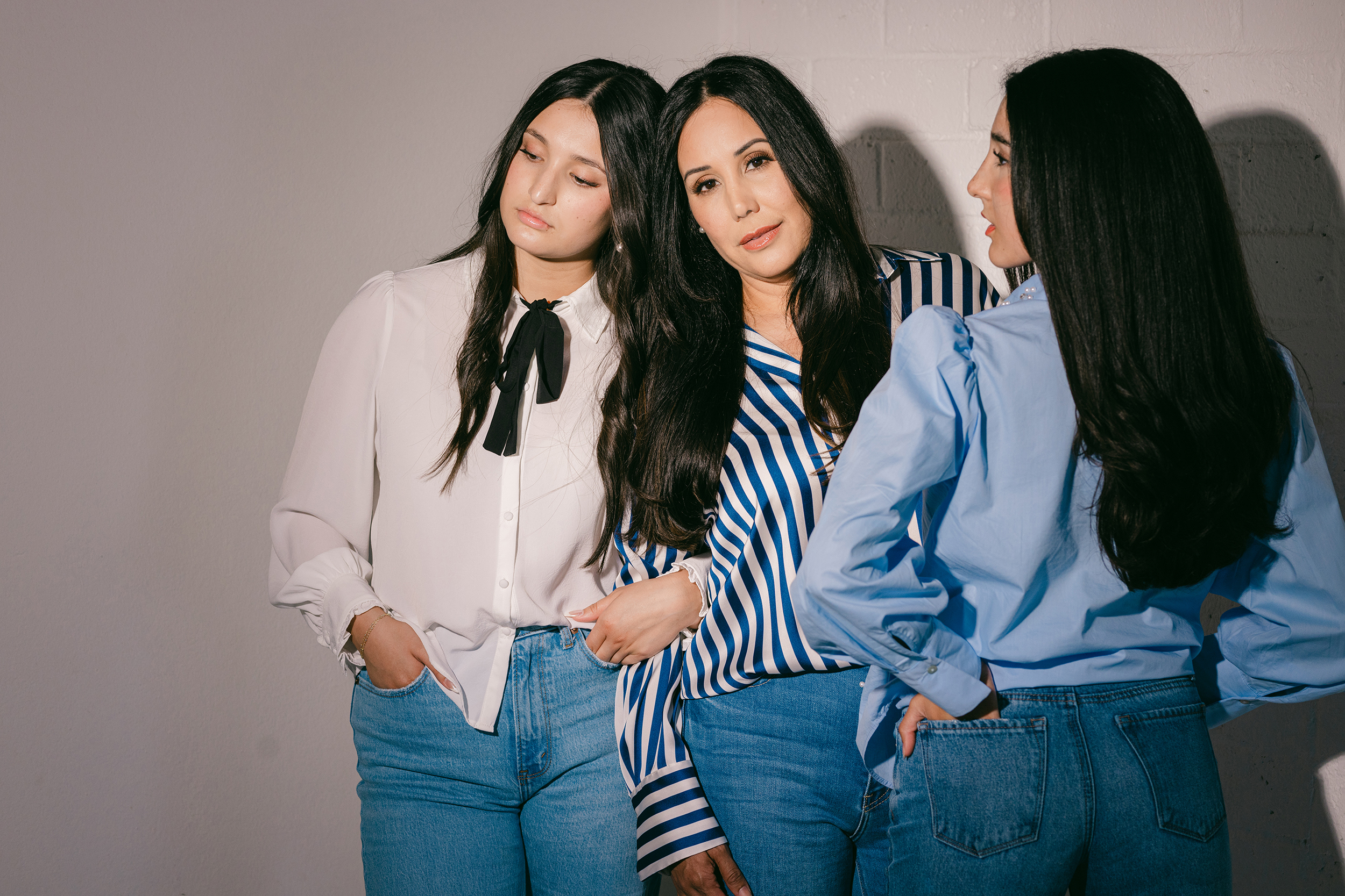 Editorial portrait of three women in coordinated denim and statement tops, captured in a minimalist studio — perfect visual storytelling for questions to ask your brand photographer before booking.