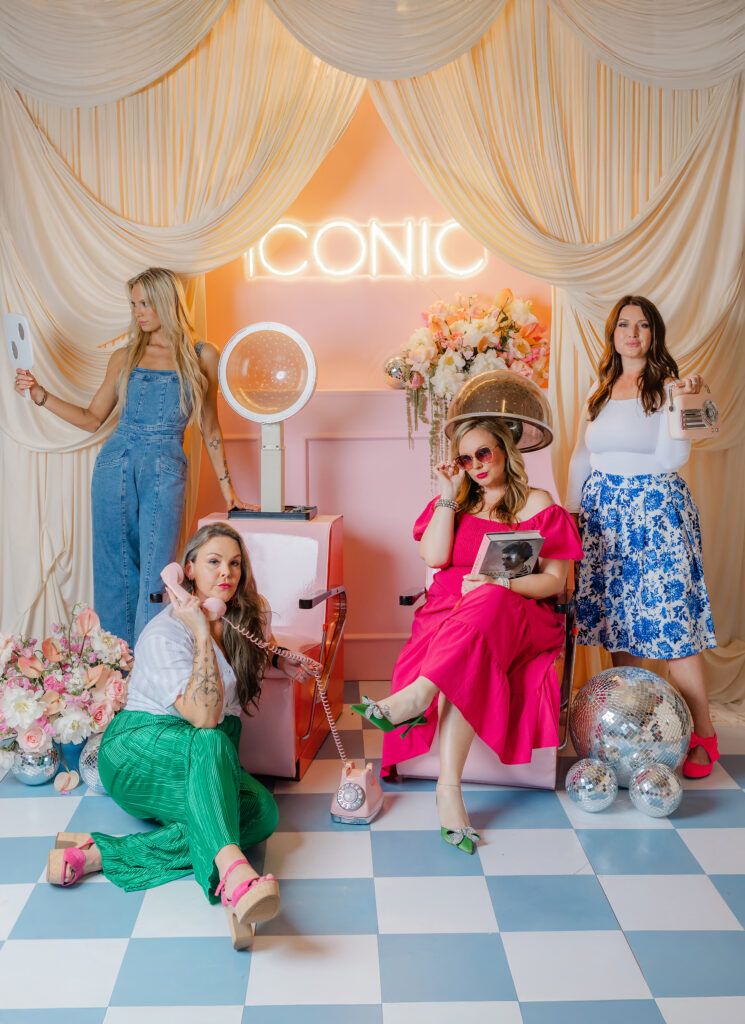 Four women pose in a vibrant, retro-inspired salon set with playful props, bold fashion, and vintage glam. Captured by Greenville South Carolina Branding Photographer Dani Lacey.