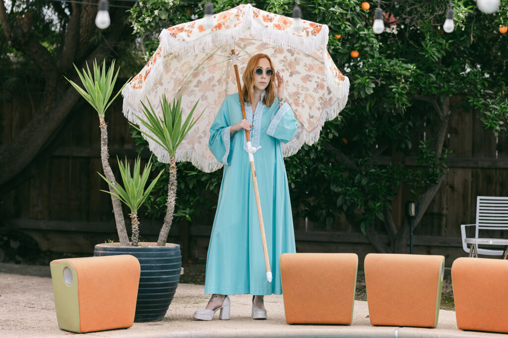 Stylish woman in a flowing blue dress holding a floral parasol during a retro editorial branding session by the pool in Greenville SC, photographed by Dani Lacey.