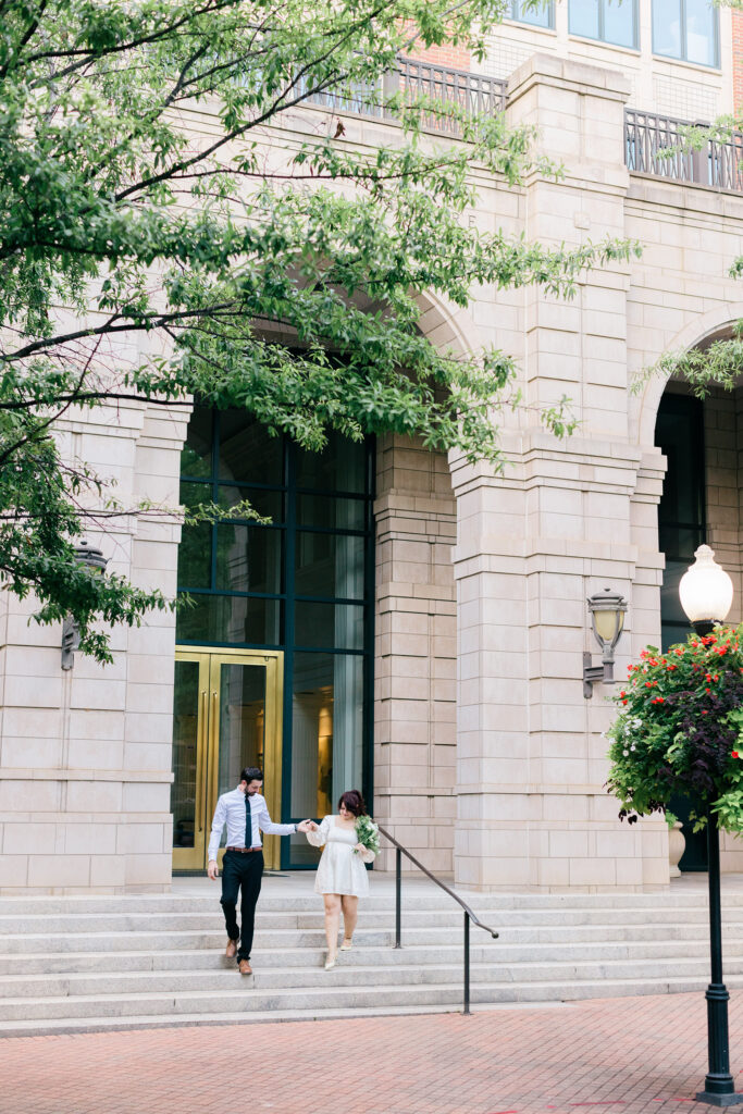 Bride and groom walk hand in hand down courthouse steps in downtown Spartanburg after their ceremony. Captured by Greenville SC wedding photographer Dani Lacey Photographs.
