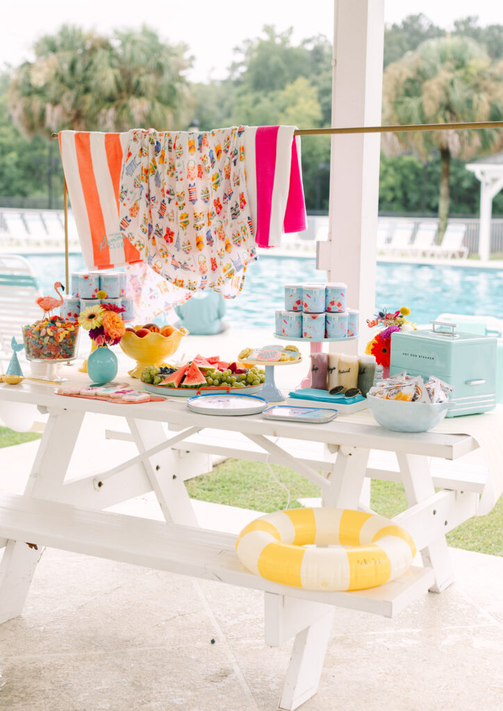 Poolside picnic setup with fruit, towels, florals, and snacks at a stylish summer kids birthday party in South Carolina. Captured by Dani Lacey Photographs.