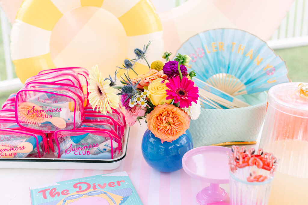 A vibrant display of colorful party favors, fresh summer florals, and playful poolside accessories at a kid’s birthday bash. Photographed by Dani Lacey Photographs.
