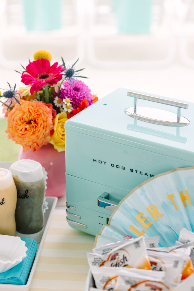 Vintage hot dog steamer with floral centerpiece and poolside condiments styled for a retro-themed kids party. Greenville South Carolina portrait photographer Dani Lacey Photographs.