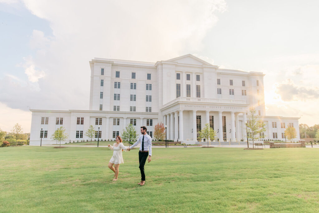 Bride and groom walk hand in hand across the lawn in front of at sunset. Greenville South Carolina wedding photographer Dani Lacey Photographs.