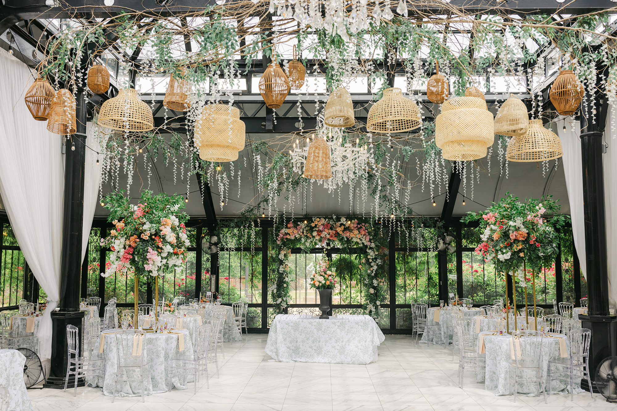 Luxury wedding reception setup at Edinburgh West in Greenville, South Carolina, featuring a glass conservatory with floral centerpieces, hanging chandeliers, rattan lanterns, and elegant garden-inspired décor – Dani Lacey Photographs