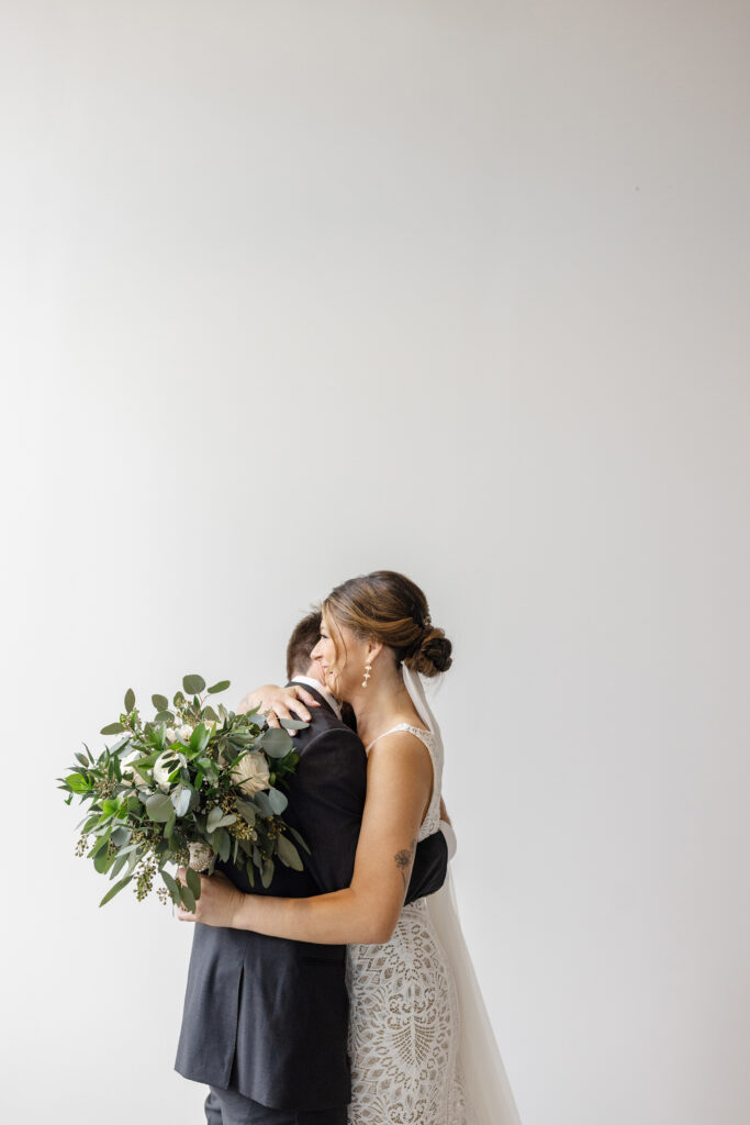 Emotional first look moment between bride and groom in Greenville, SC, bride holding bouquet of greenery and white florals, editorial wedding photography – Dani Lacey Photographs