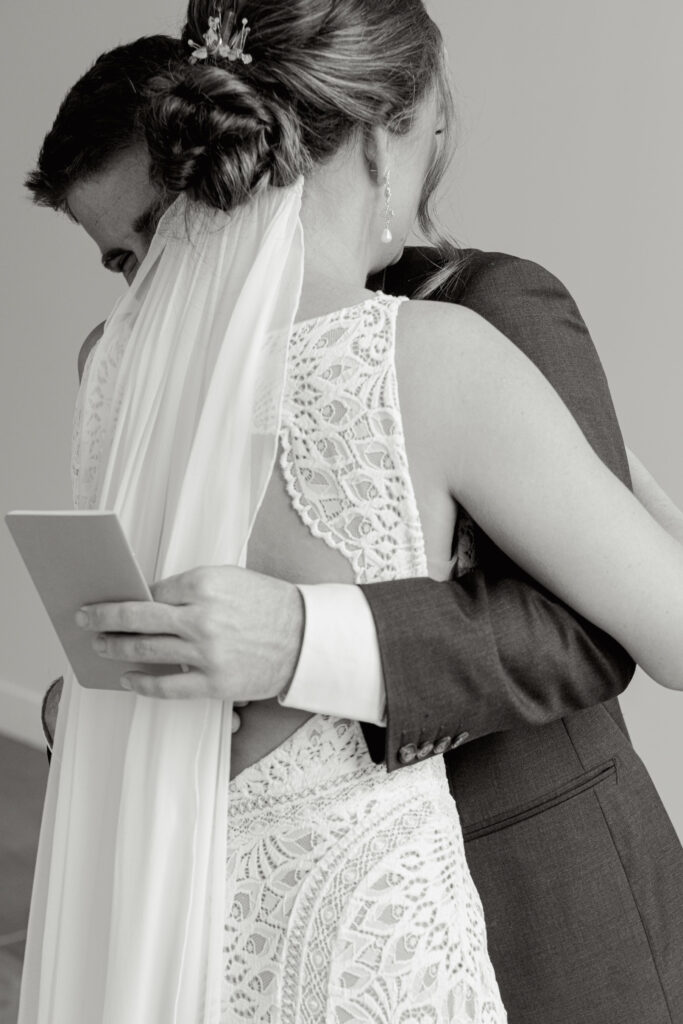 Black and white photo of bride and groom hugging tightly after exchanging vows during first look.