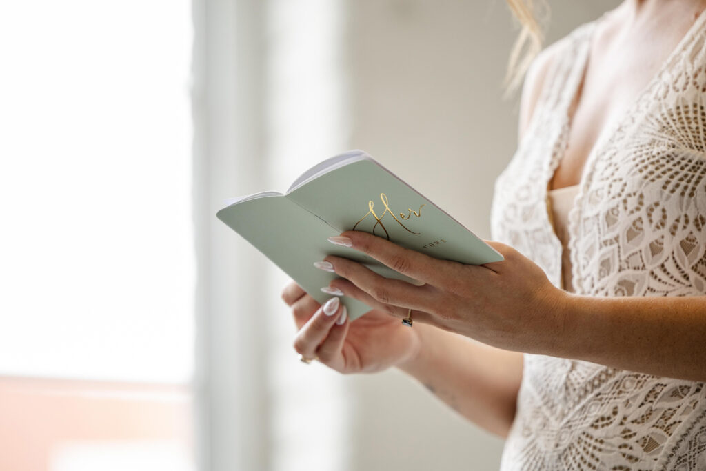 Bride reads personal vows from a vow book during first look at Judson Mill in Greenville South Carolina.