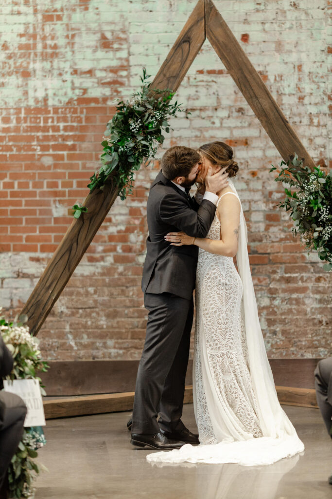 Bride and groom sharing their first kiss as a married couple at Judson Mill Greenville wedding | Dani Lacey Photographs