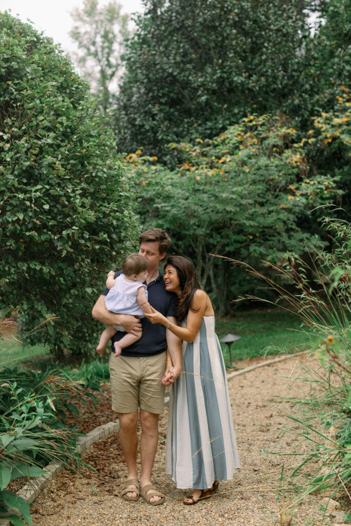 A family shares laughter while walking a garden path during Greenville SC Family Portraits at Furman University. Dani Lacey Photographs.