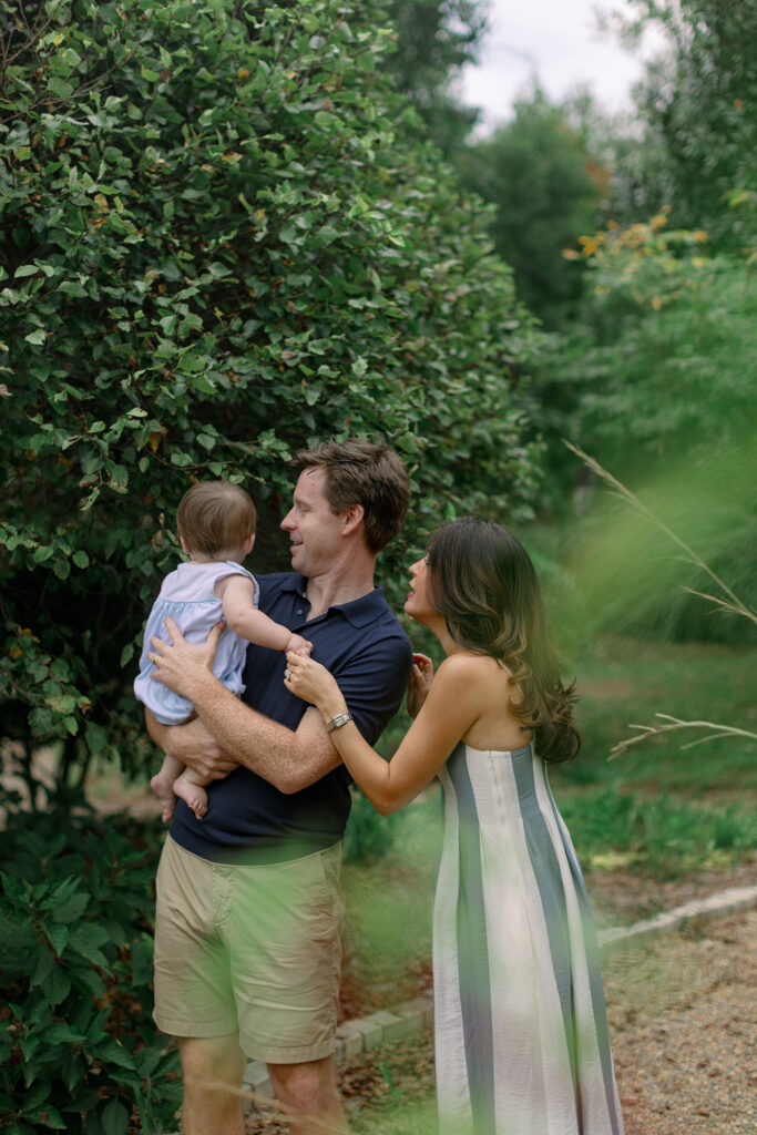 A family enjoys a quiet moment surrounded by lush greenery during Greenville SC family portraits at Furman University. Dani Lacey Photographs.
