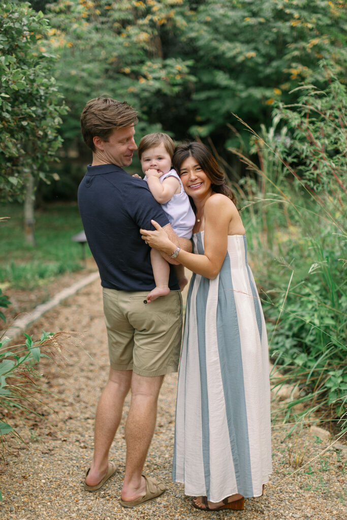 A smiling family stands together on a garden path at Furman University
