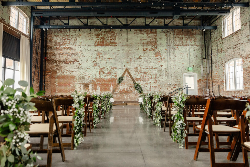 Industrial wedding ceremony setup at Judson Mill with greenery aisle decor and a geometric arch | Dani Lacey Photographs