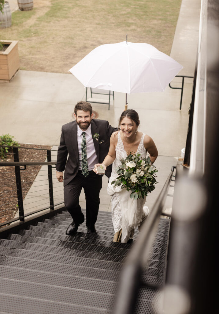 Bride and groom laugh together under an umbrella at their Judson Mill wedding in Greenville, South Carolina. Dani Lacey Photographs.