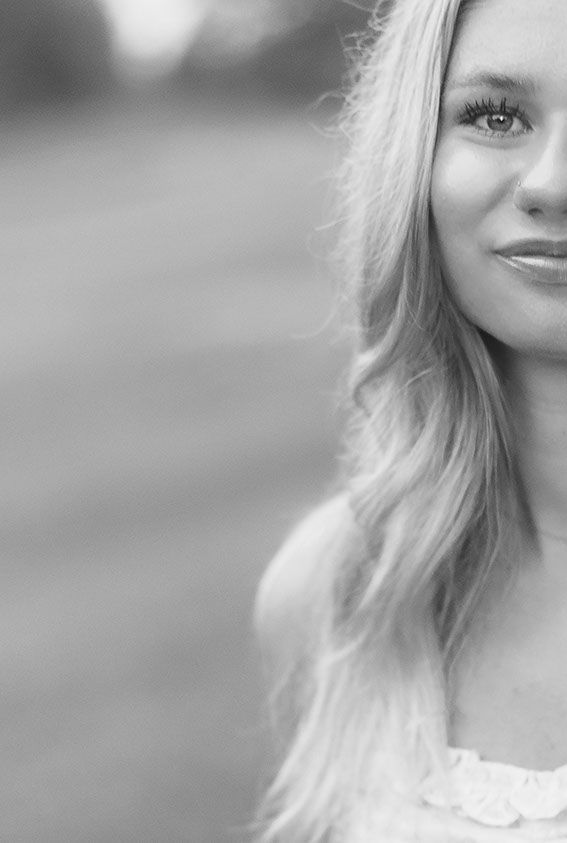 Black and white close-up portrait of a woman smiling softly during a Greenville SC at-home session. Dani Lacey Photographs.