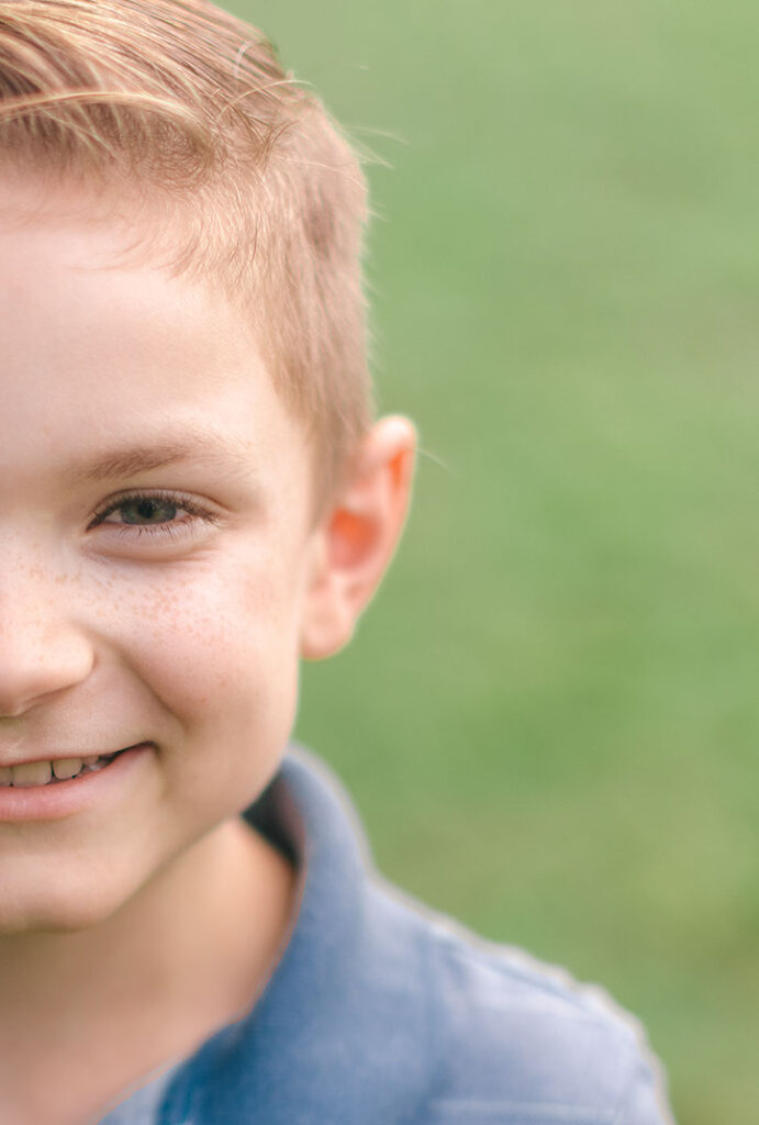 Close-up portrait of a young boy smiling softly during a Greenville SC at-home family photoshoot. Dani Lacey Photographs.