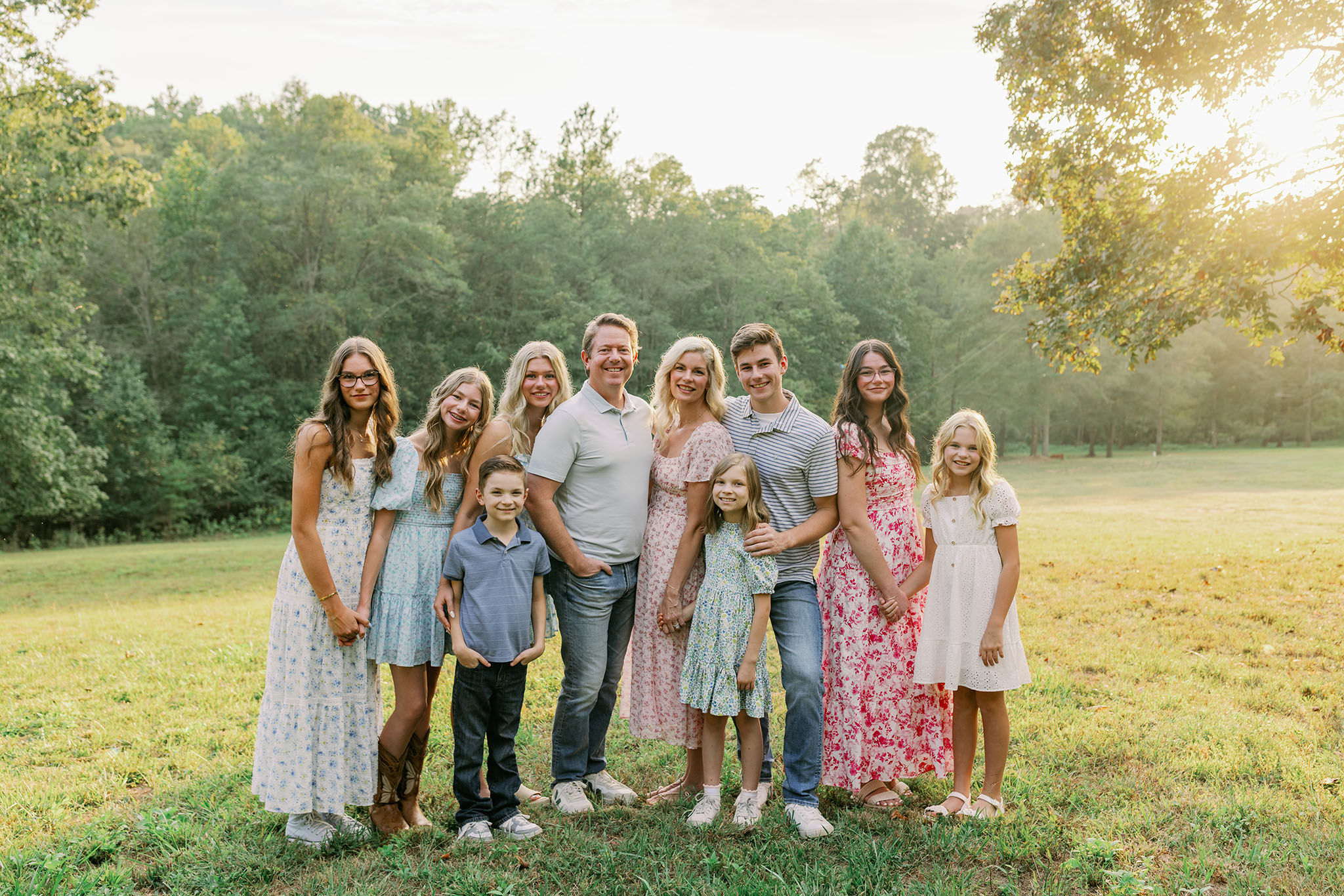 Family of ten smiling together in a golden field during sunset on their property in Greenville SC. Dani Lacey Photographs.