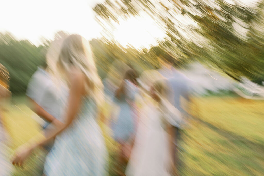 Creative motion blur of family walking together outdoors during golden hour.