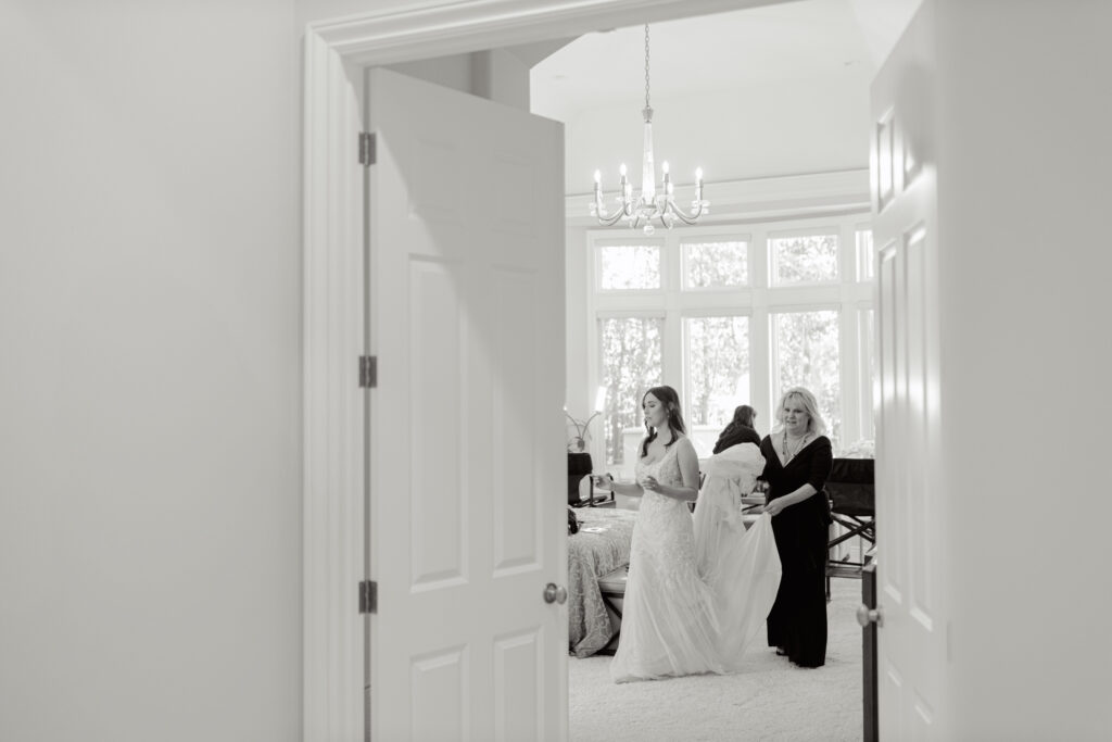 Bride getting ready with her mother helping adjust her wedding dress in a bright, elegant room during a Greenville, South Carolina wedding morning.