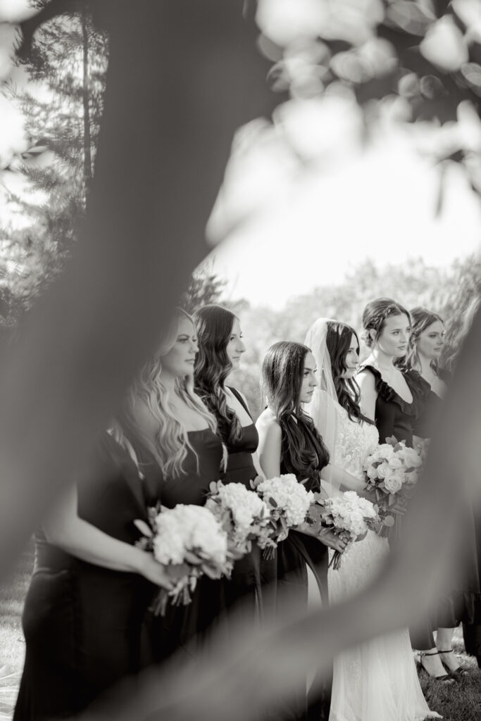 Bride and bridesmaids standing together during the ceremony in South Carolina, holding bouquets.