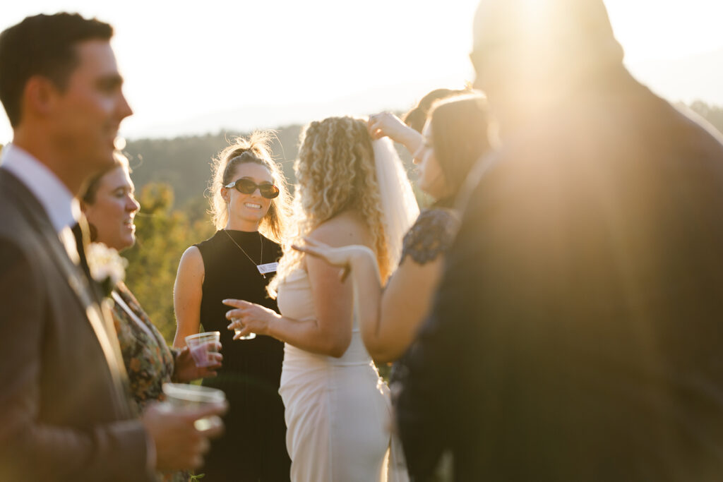 Guests chatting and laughing during golden hour cocktail hour at an outdoor South Carolina wedding, with warm sunset light and candid energy.