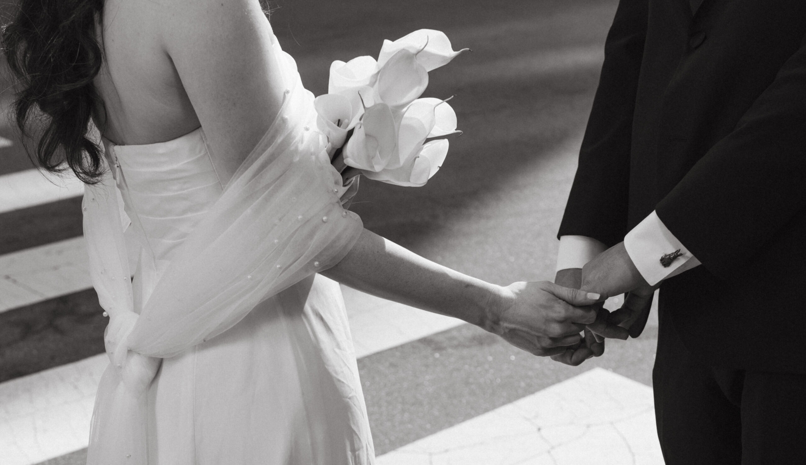 Bride and groom holding hands crossing street