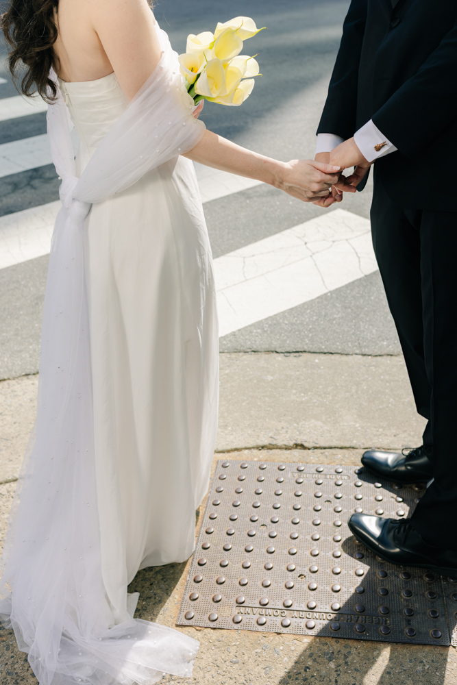 Bride and groom holding hands crossing street