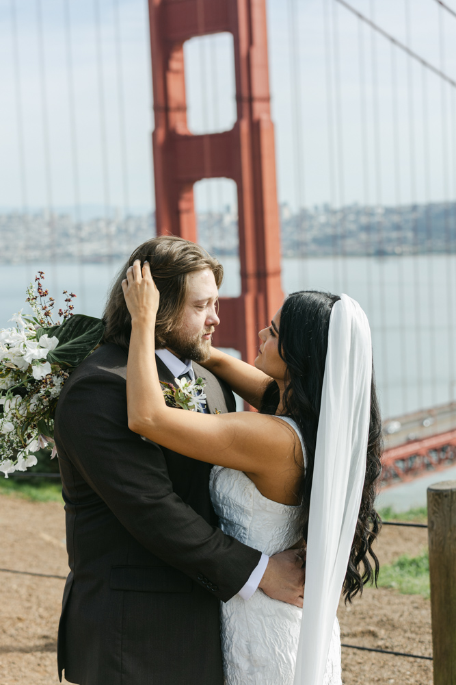 bride fixing grooms hair overlooking golden gate bridge