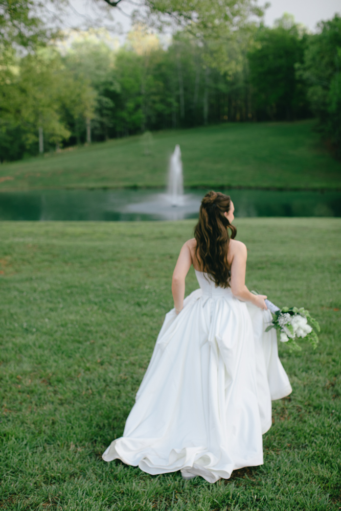 Bride walking beside pond at wedding venue