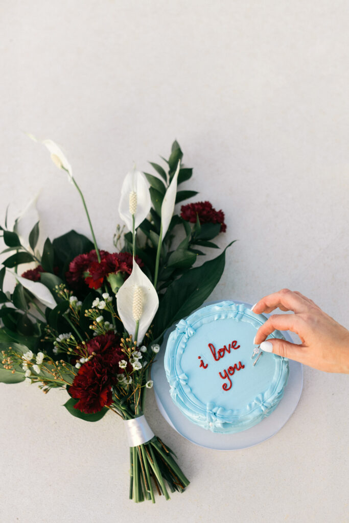 Blue wedding cake beside colorful bridal bouquet