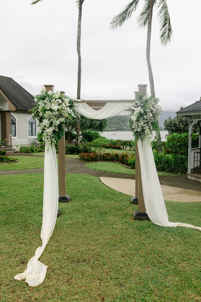 White floral ceremony arch overlooking the water