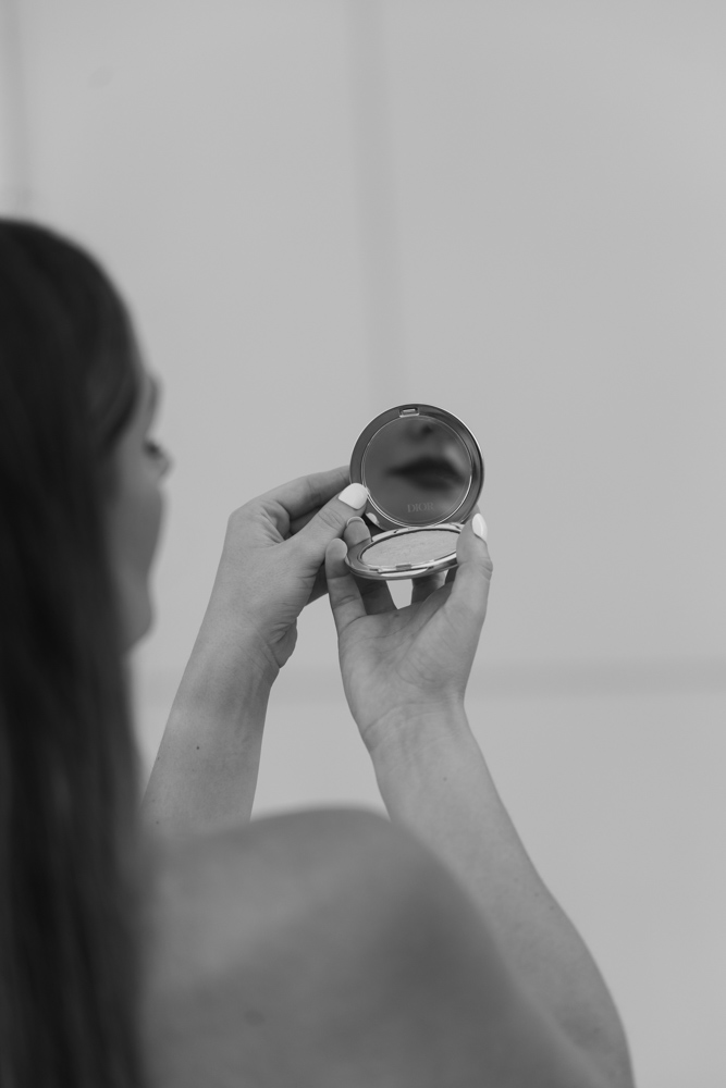 Bride holding compact mirror before portraits