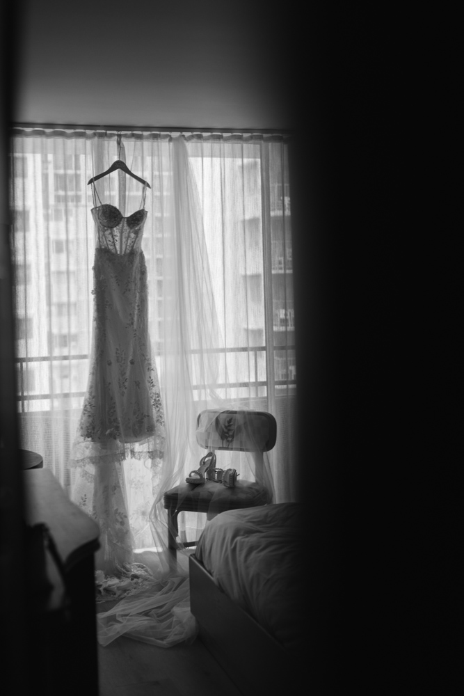 Wedding dress hanging in hotel room before ceremony