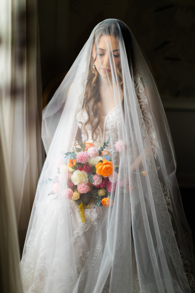 Bride holding colorful bouquet beneath veil