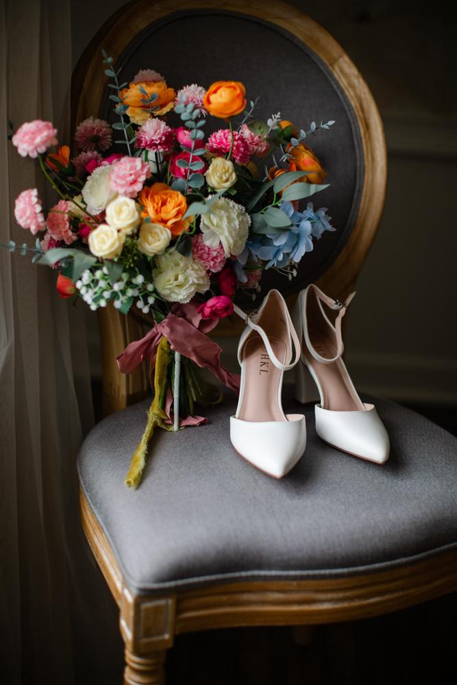 Bridal shoes beside colorful wedding bouquet