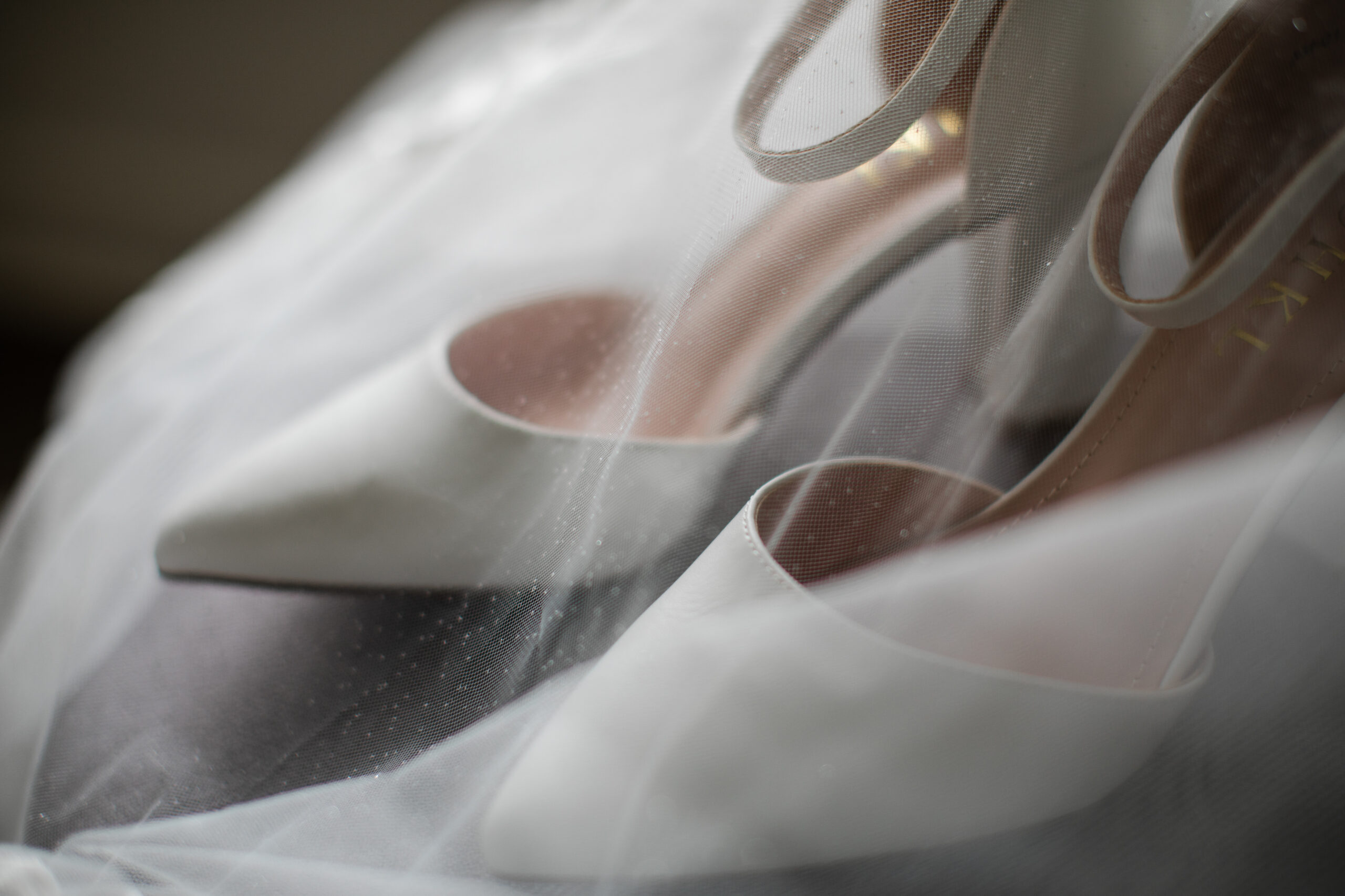 White bridal shoes beneath a wedding veil