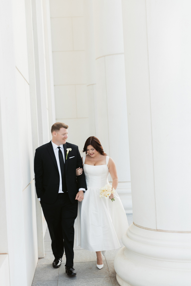 Bride and groom walking beneath courthouse columns
