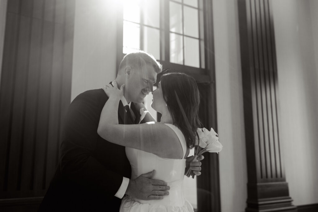 Bride and groom embracing in front of courthouse windows