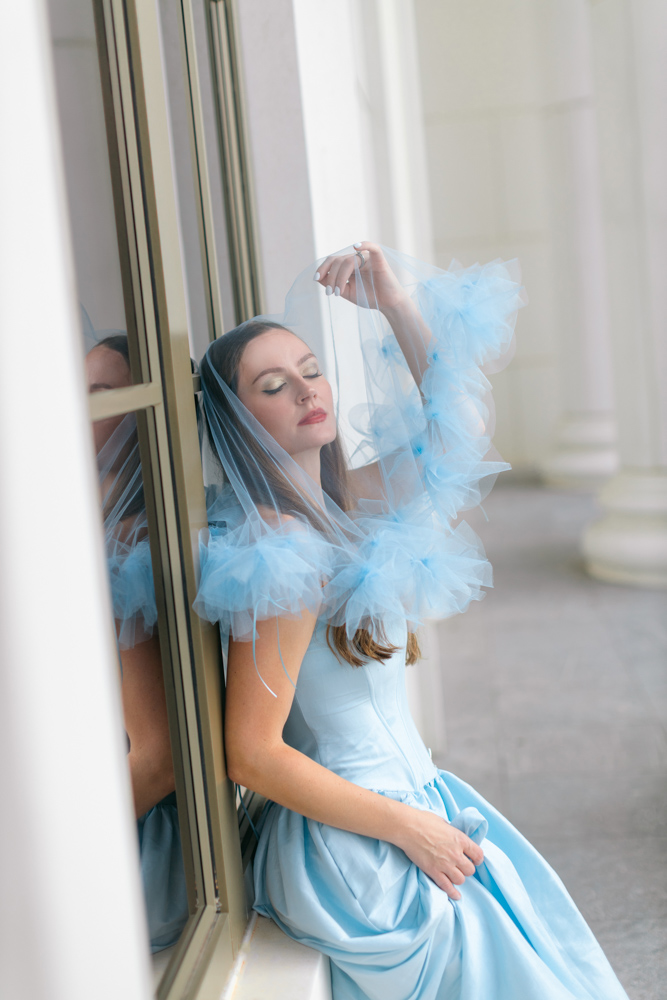 Bride sitting in window wearing blue veil