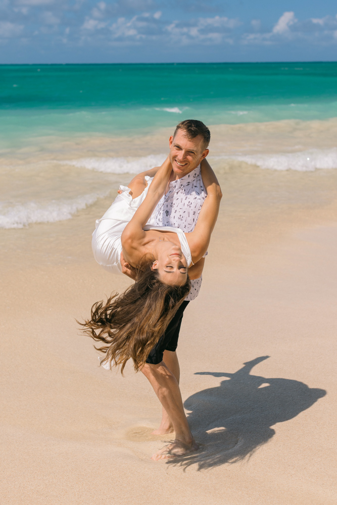 Groom spinning bride on an Oahu beach